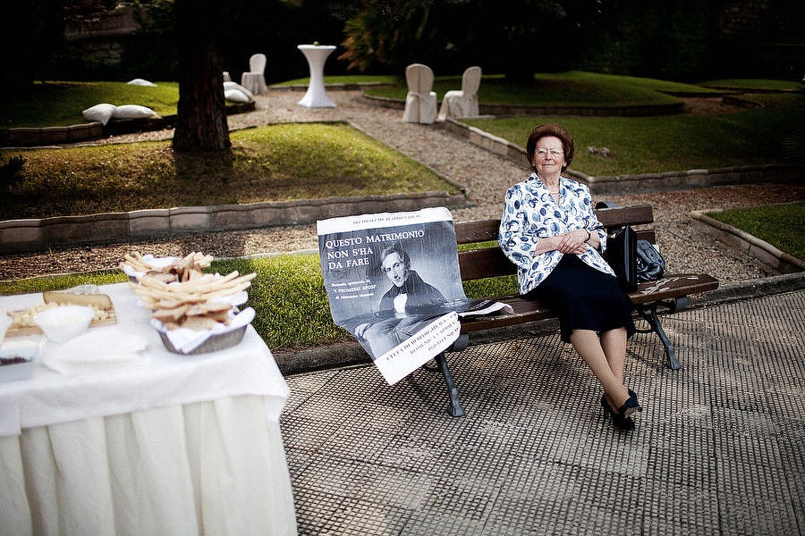 old woman sitting on a bench at an italian wedding