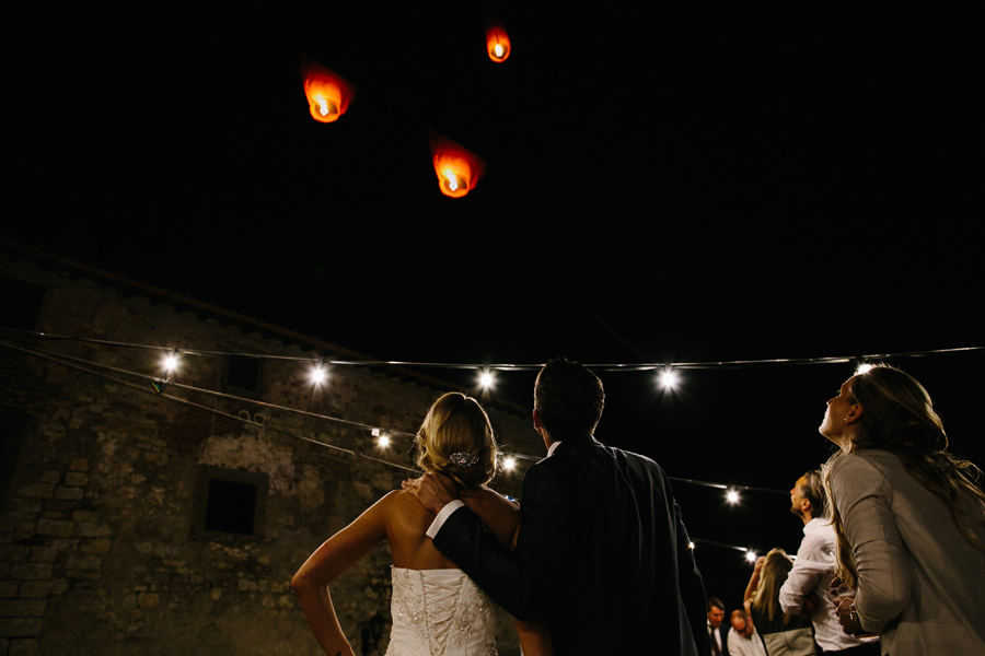 Bride and groom watching flying paper lanterns at wedding in Ita