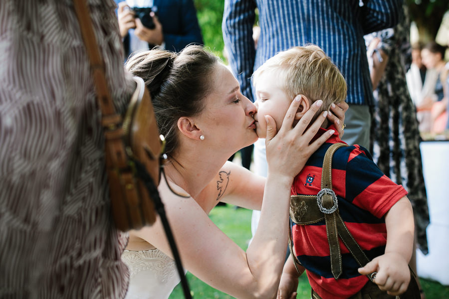 braut küsst einen kleinen jungen während hochzeit