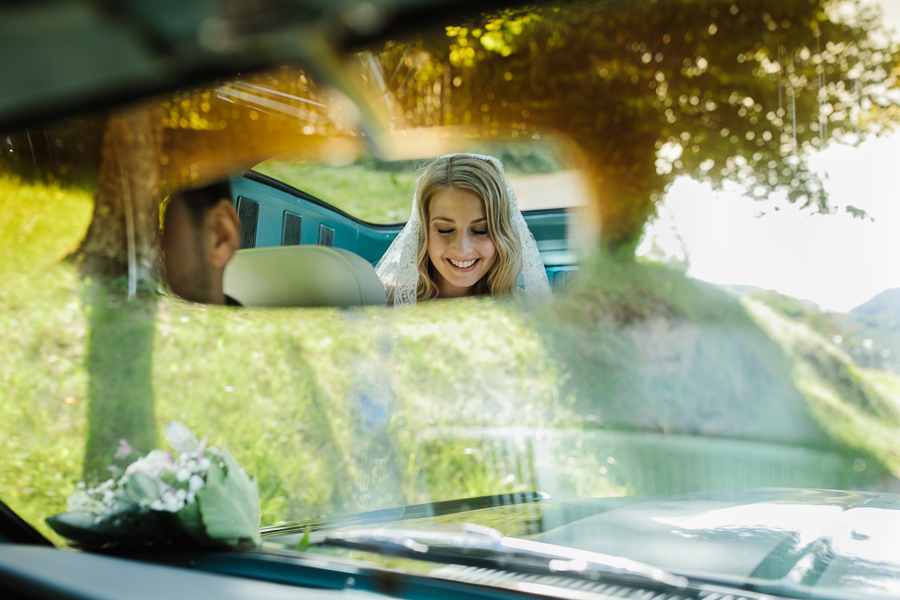 bride through mirrir in mustang car driving to ceremony church