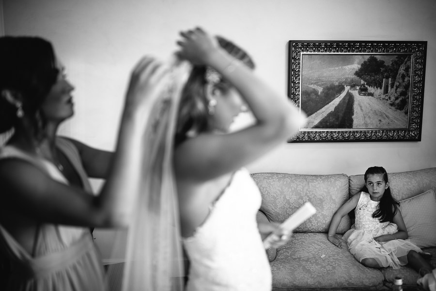 little girl watching bride putting veil on