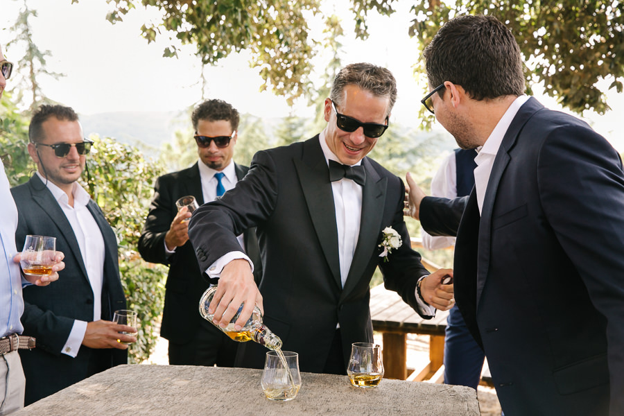 Groom and groomsmen having a drink before wedding