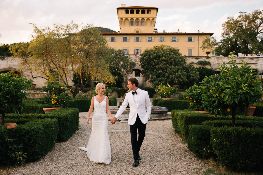 bride and groom walking together through the garden in fiesole